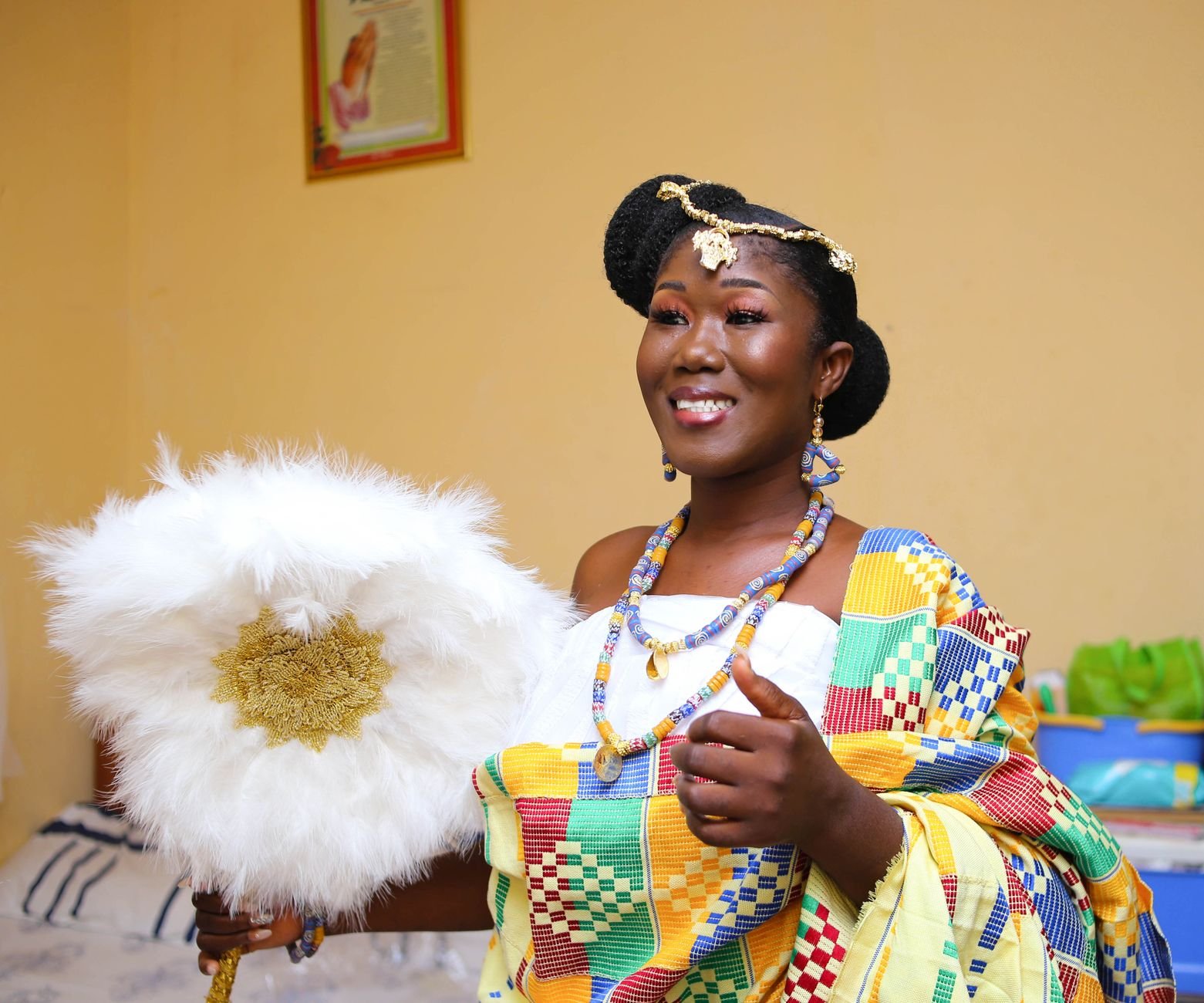 Smiling African woman in colorful, traditional attire during a festive celebration.